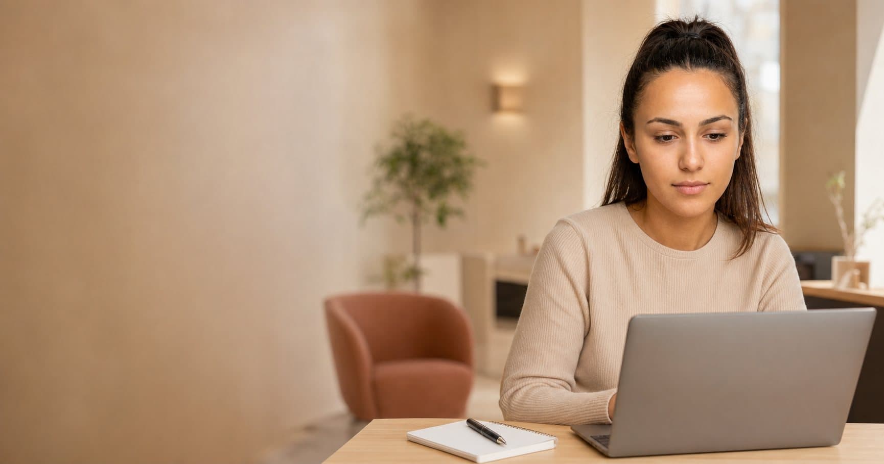 Eine junge Frau sitzt am Schreibtisch und sucht am Laptop nach einer neuen Stelle